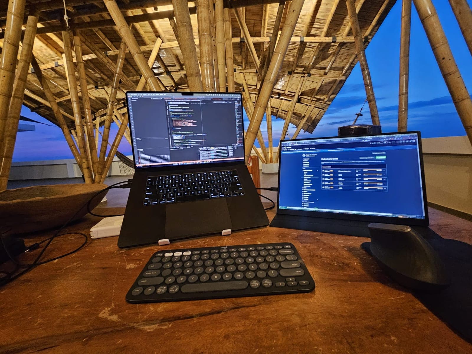 Laptop, second screen and keyboard set up for remote work on the bamboo rooftop terrace