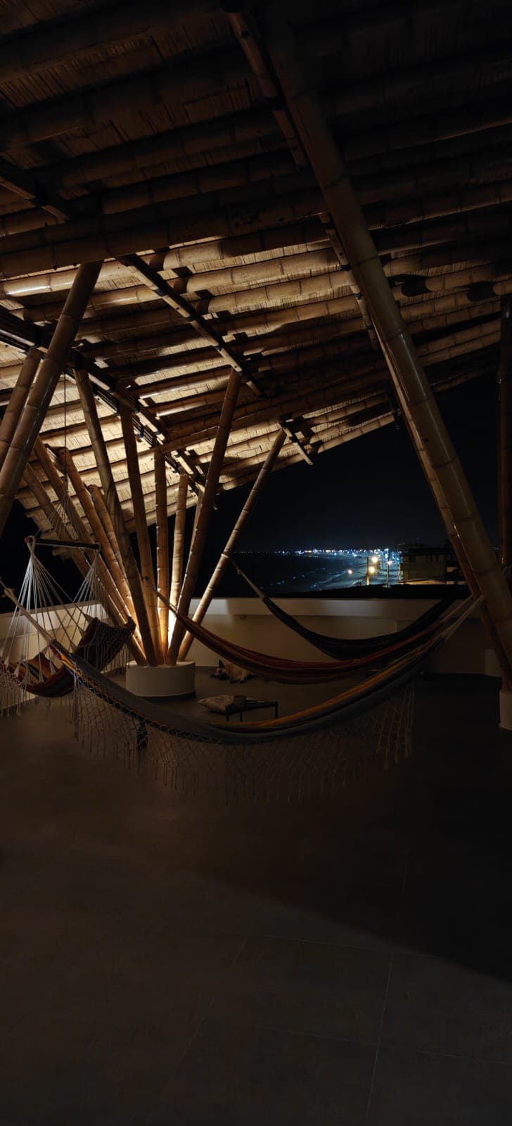 Rooftop terrace at night with hammocks under the bamboo roof