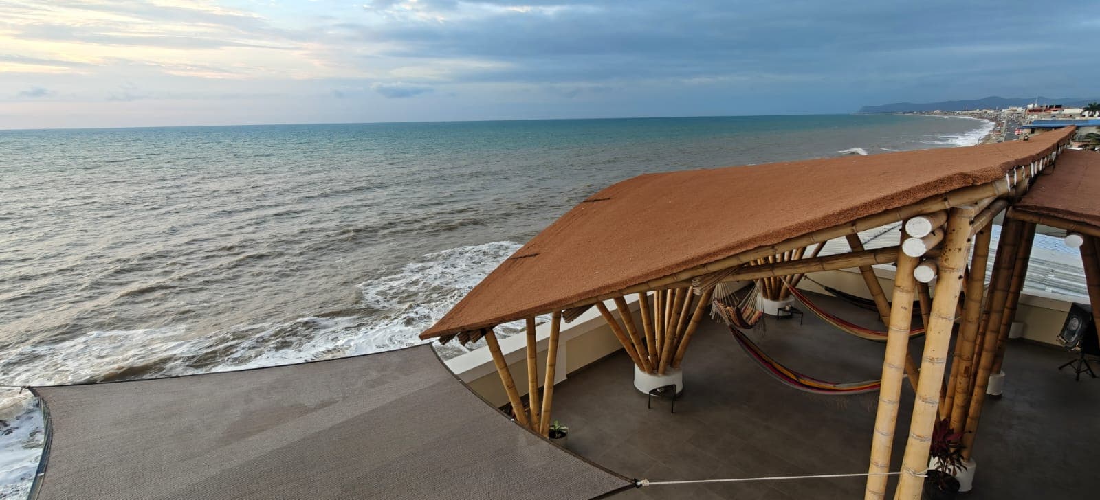 Bamboo roof terrace of Hostal Cruzita above the beach and waves