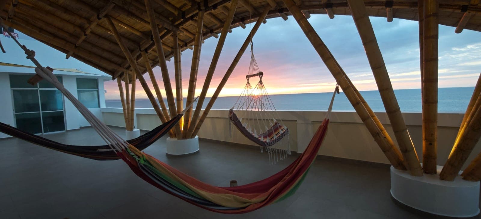 Hammocks on the rooftop terrace at sunset, with the ocean behind