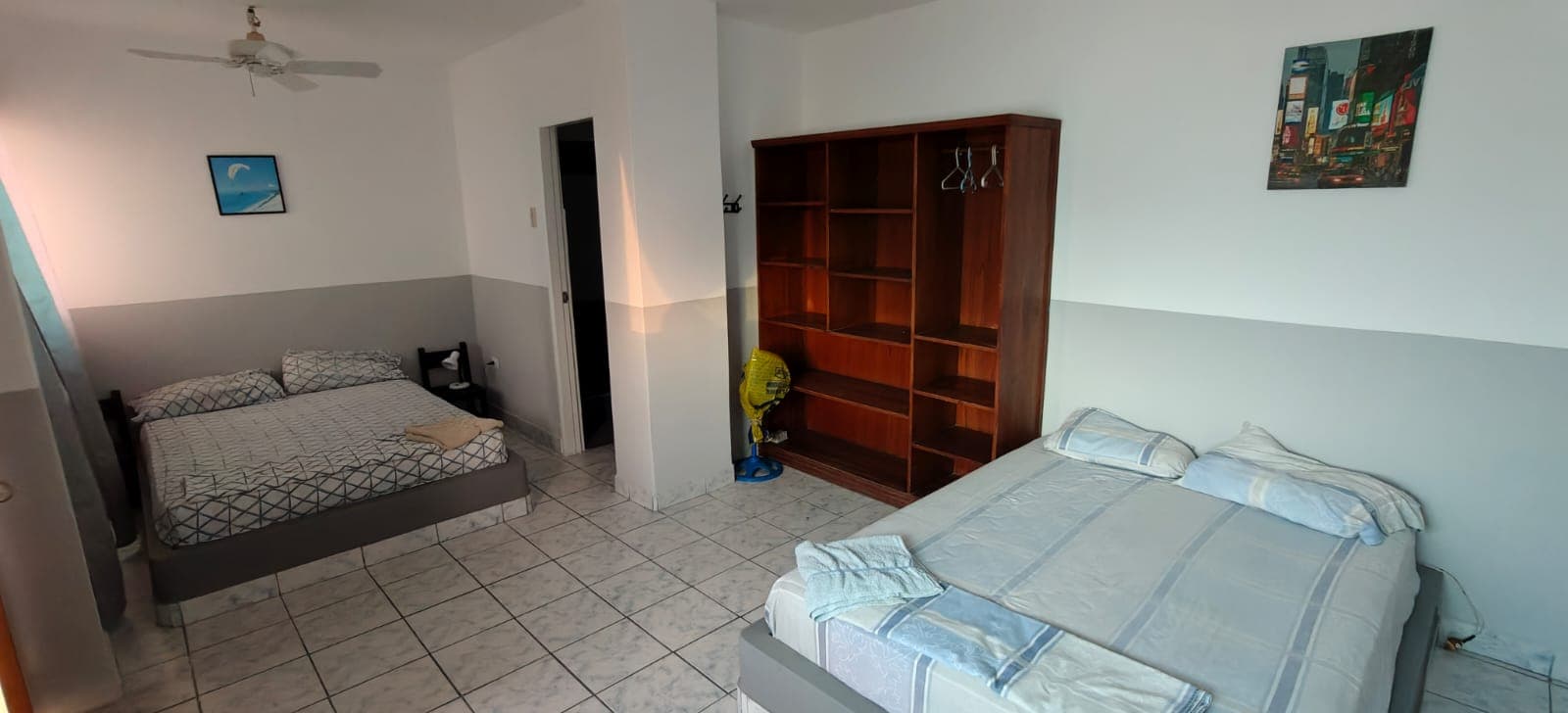 Bright room with two double beds, a ceiling fan and a wardrobe