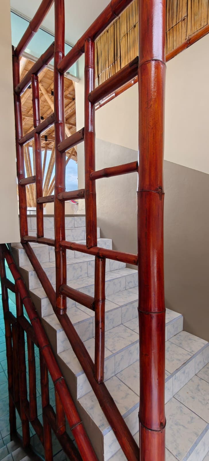 Staircase with a red bamboo railing inside Hostal Cruzita